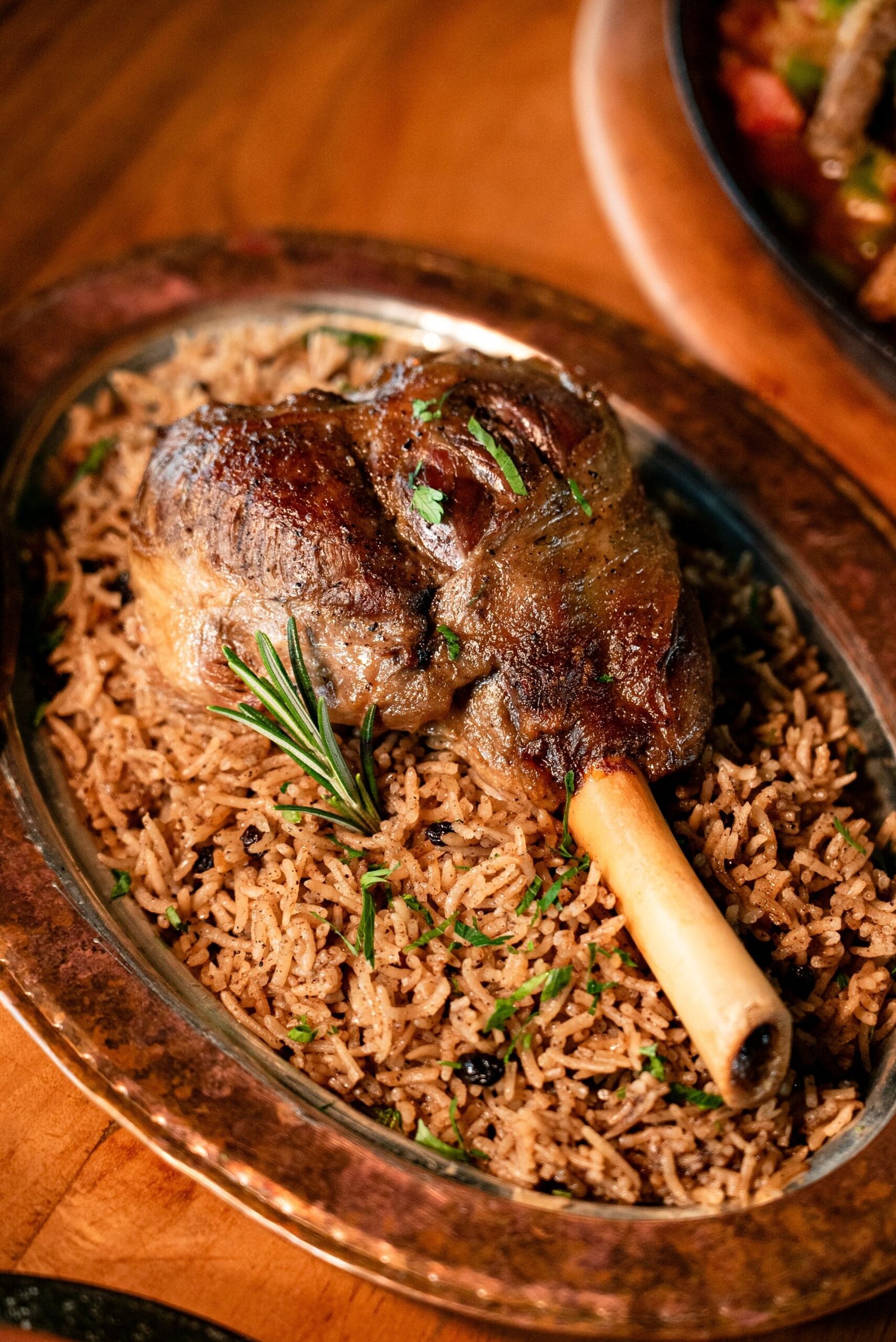 Delicious roasted lamb shank served on a bed of aromatic spiced rice with rosemary.